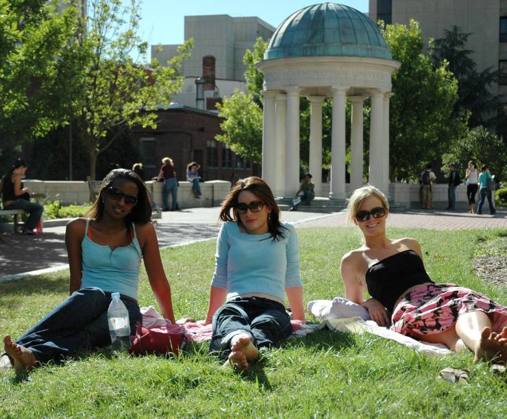 Three female students sitting in grass in Kogan Plaza.