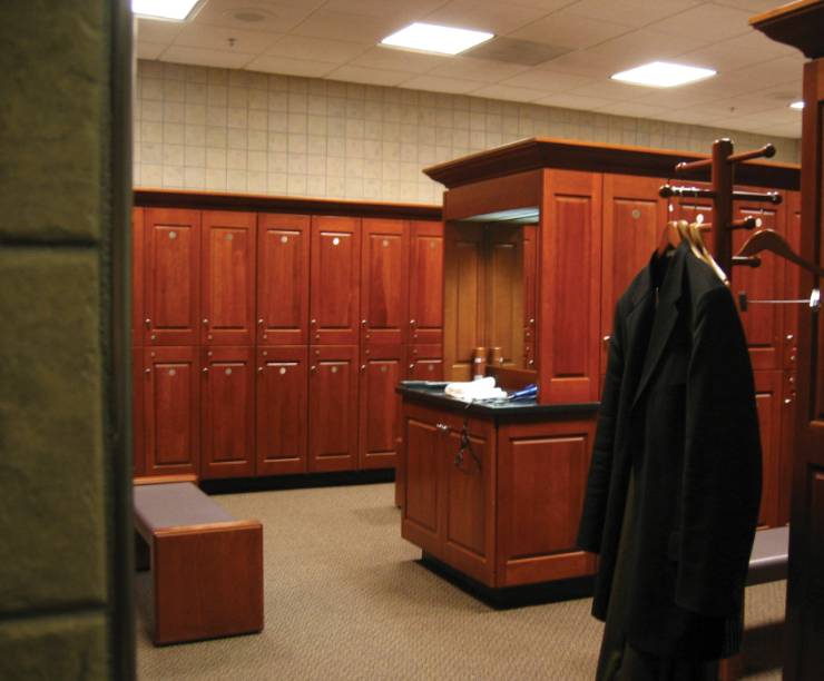 A wood-paneled locker room with a coat hanging in the foreground.