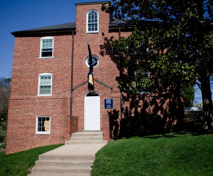Cole Hall, a red brick building with GW flag in front, as seen from front of building.