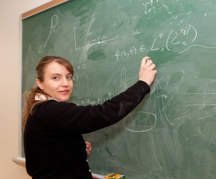 A professor writes on a chalk board.