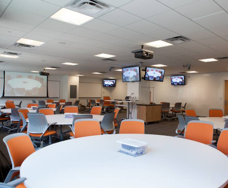 A classroom of large screens and round tables.