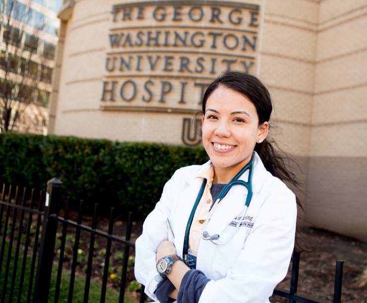 Nurse in lab coat stands in front of GW hospital