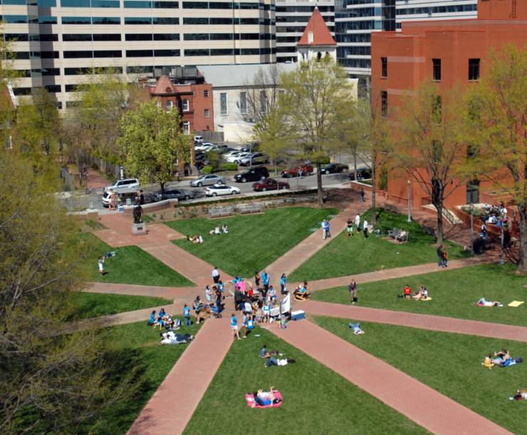 A green open space surrounded by brick buildings with brick paths converging in its center.