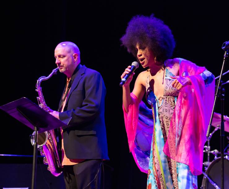 A jazz singer and saxophonist perform onstage.