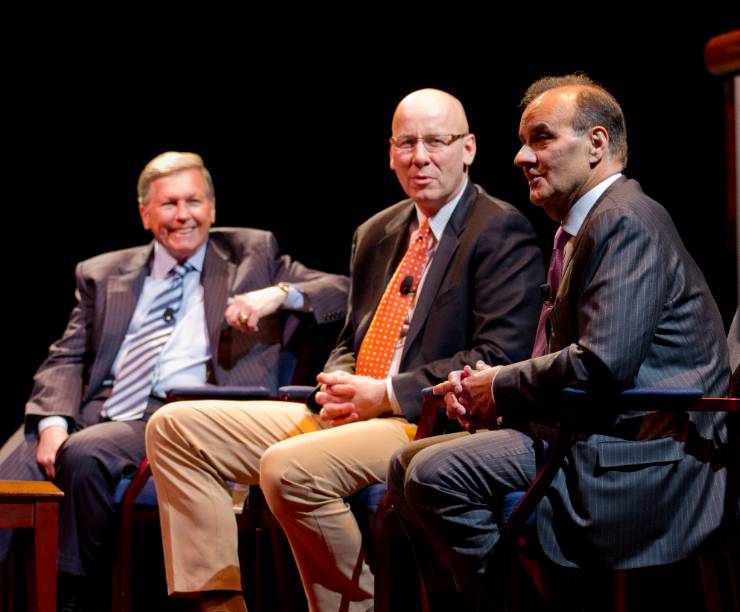 Joe Torre sits onstage speaking with three other men.