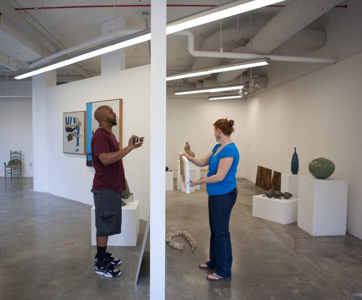 Students install artwork in an open gallery space.