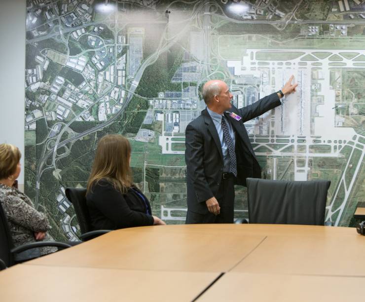 A man speaks to a table of people in front of a map of Dulles Airport.