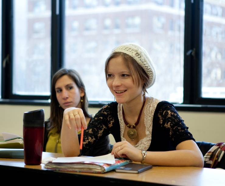 Two women sit with notebooks open in class.