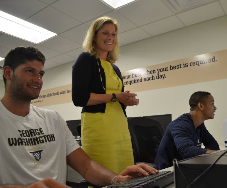 Student athletes work in a computer lab with an advisor.