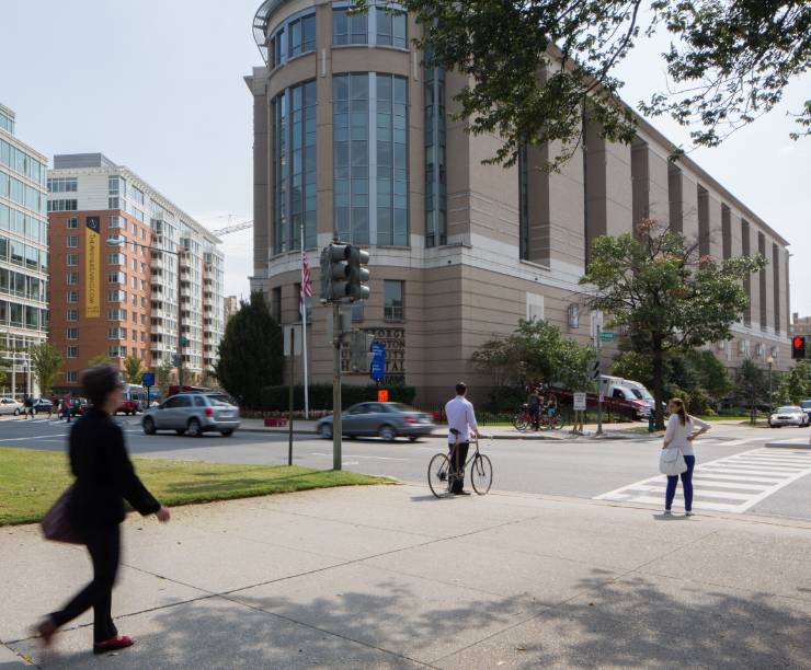 View of brick hospital building from Washington Circle. People walking and biking in cross walk.