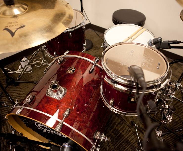A drum kit is fitted with microphones for recording.