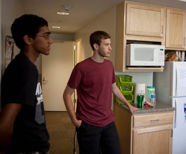 Two roommates stand in their kitchen area.