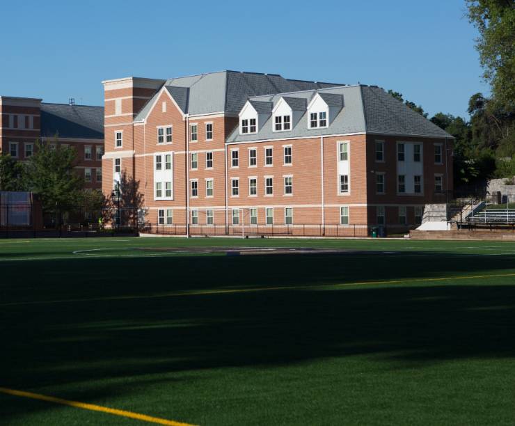 The green athletic fields stretch behind West Hall.