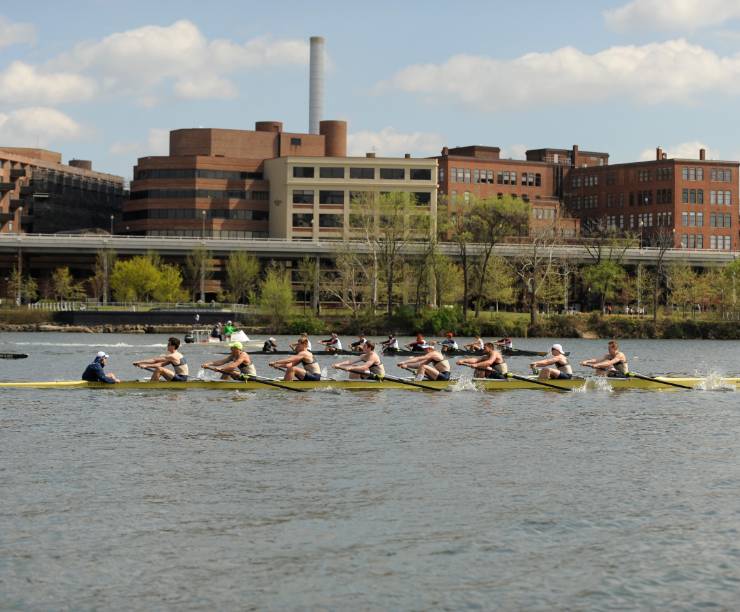 The GW Men's Rowing team rows on a river.