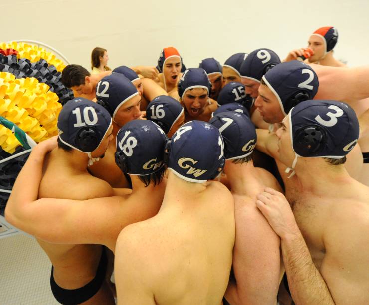Water polo players huddle on the pool deck.