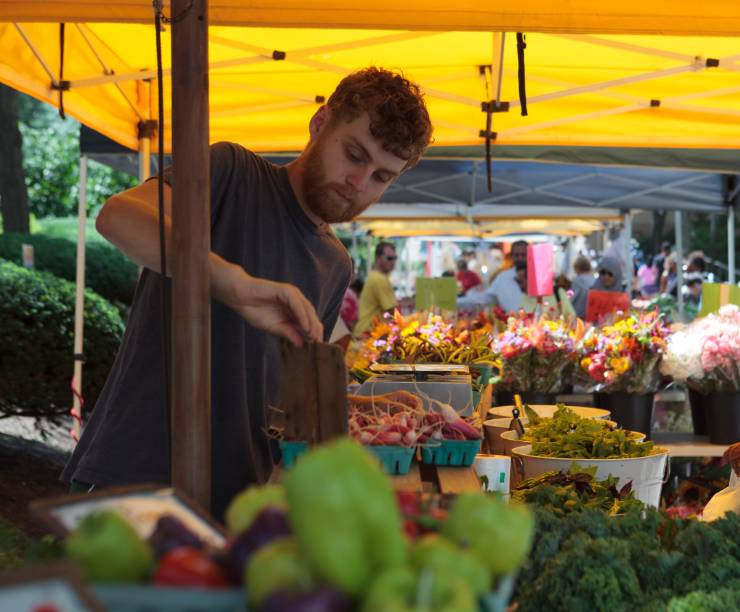 A young man works at a farm stand.