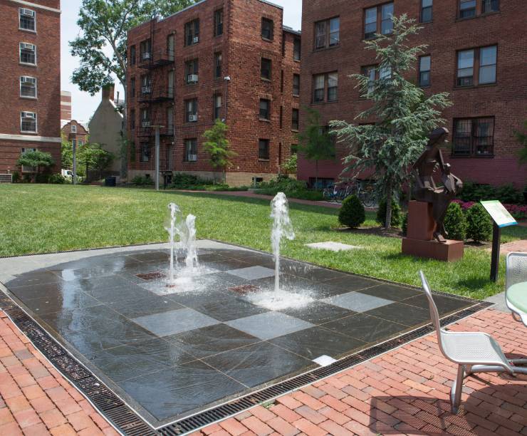 A fountain and patio seating next to the green space in Square 80.