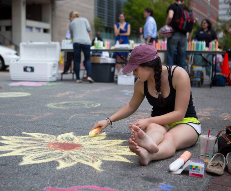 A student draws in chalk on the street.