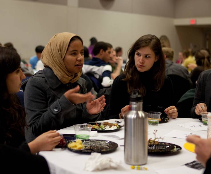 Students talk over dinner at a table.