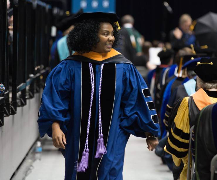 A graduate walks down the aisle at the Doctoral Hooding.