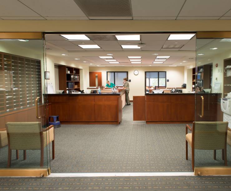 Front entrance to the Records office. The entrance includes glass doors, shelves with paper forms and a front desk staffed by multiple staffers.