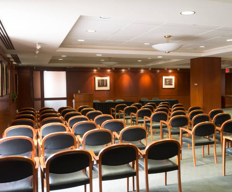 GW Law's Faculty Conference Center features wood paneling with rows of seats set up facing a podium.