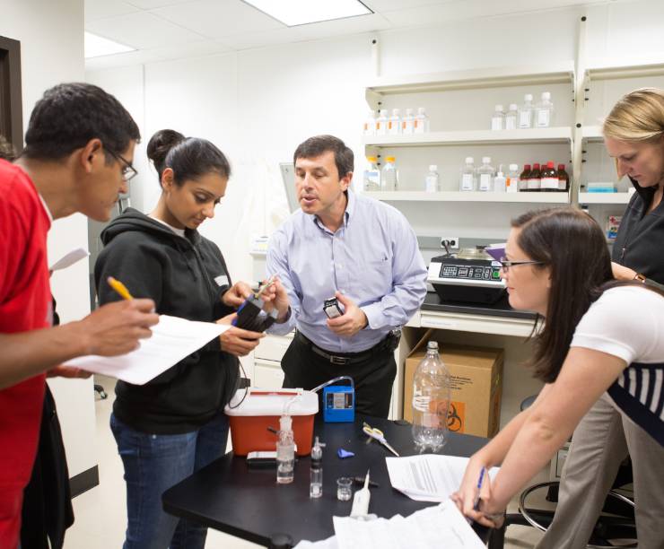 Students talk with a professor in a laboratory class.