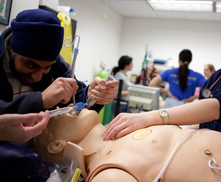 A medical student intubates a dummy while another student looks on.