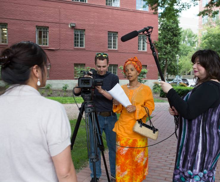 Students with a camera and sound gear film a woman.