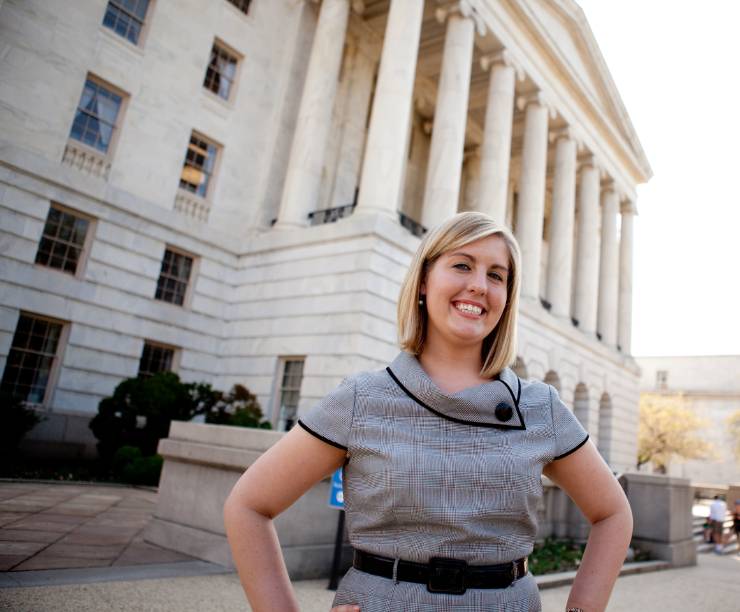A student stands in front of a building on Capitol Hill.