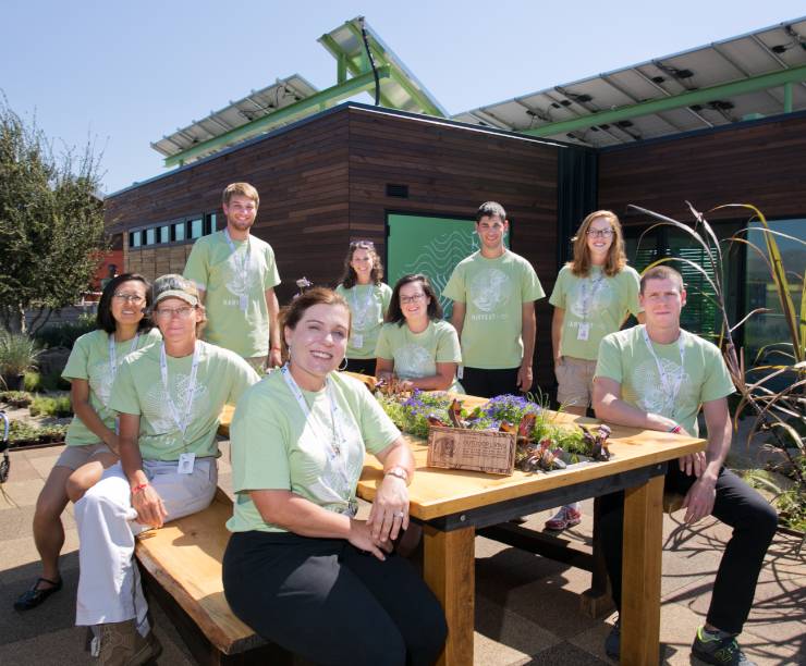 Team members stand in front of the sustainable home they built.