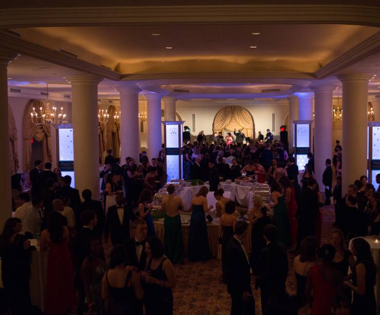Dinner and dancing are underway in an elegantly lit ballroom.