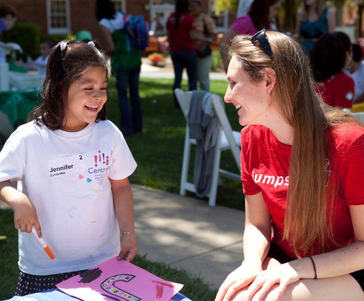 A GW student smiles with a young girl.