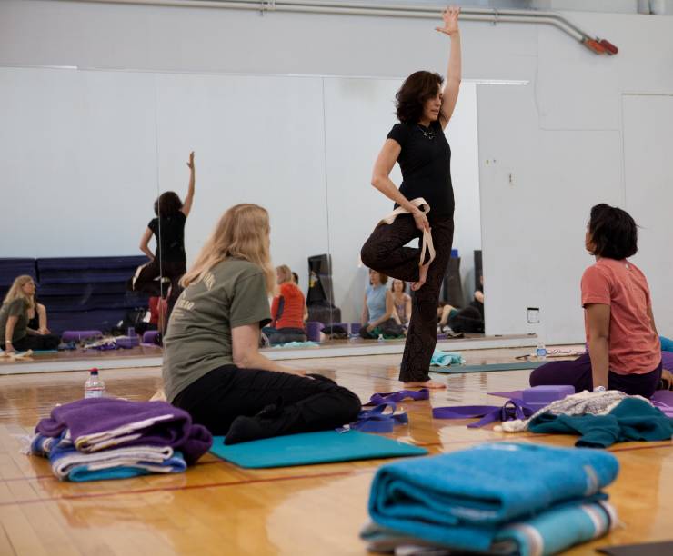 A yoga teacher demonstrates a pose to her students.