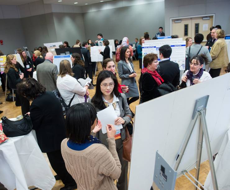 Crowds of students and alumni gather for a conference where they are sharing research findings and discuss work with their peers.
