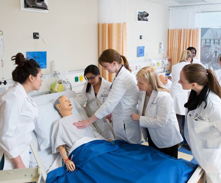 Group of nursing students examine a simulation mannequin in the simulation laboratory.