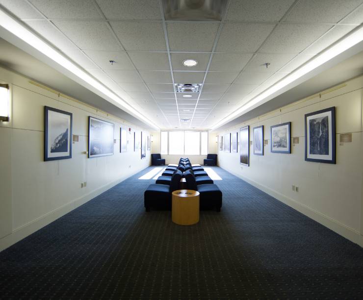 An open hall space has chairs in the center and photographs on the walls.