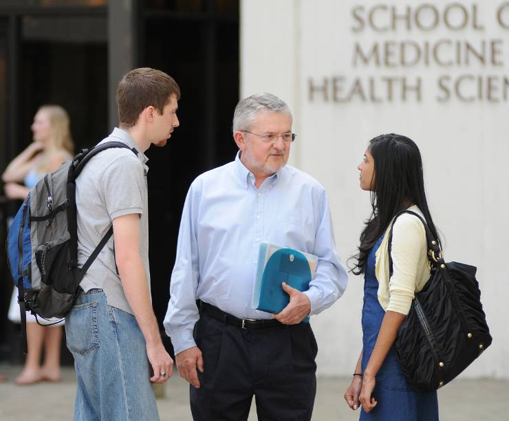 A professor speaks with students outside Ross Hall.