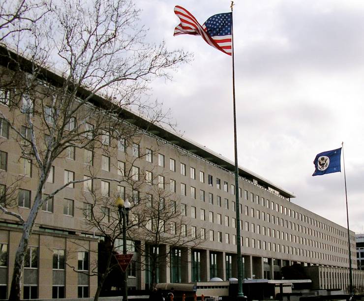 The State Department Building with a US flag flying in front.