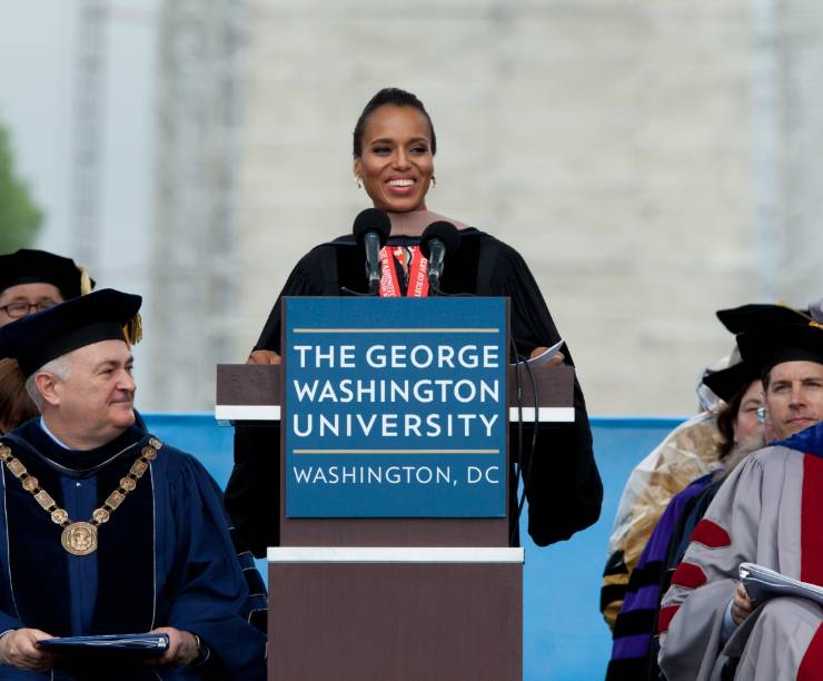 Actress Kerry Washington speaks at the GW podium on stage at commencement with the Washington Memorial in the background.