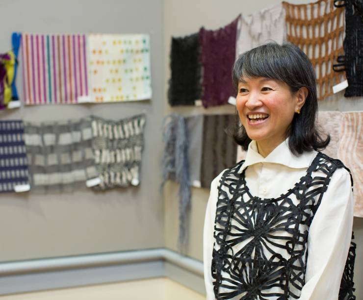 Nuno CEO Reiko Sudo speaks in front of a display of her fabrics.