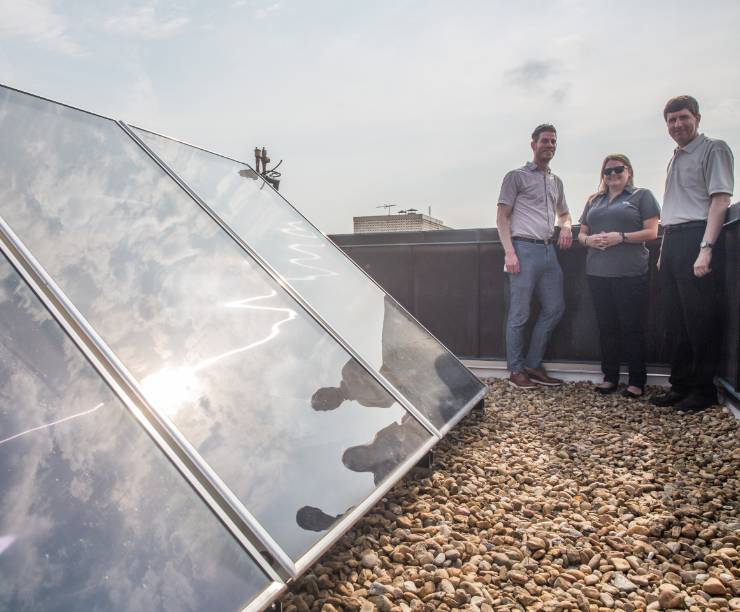 Members of the sustainability team stand by solar panels.