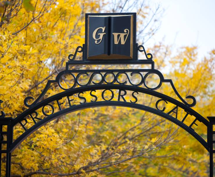 A view of Professor's Gate with yellow fall foliage behind.