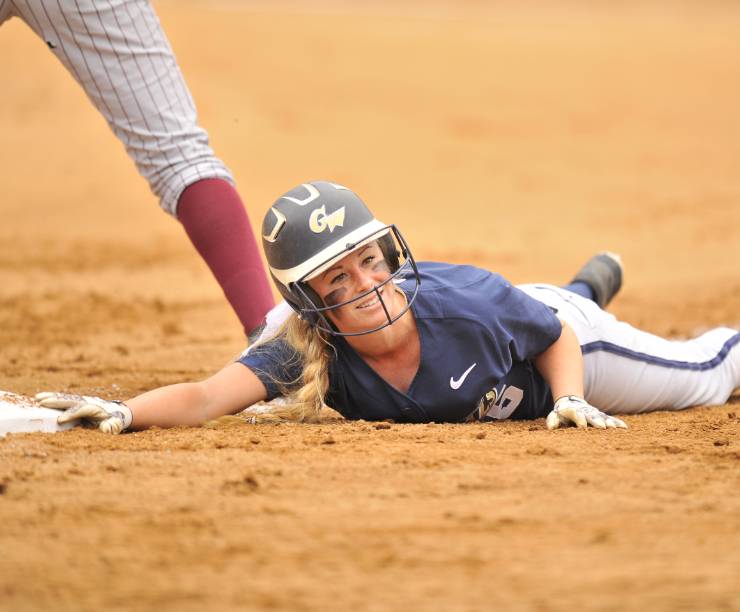 A softball player slides into a base on her side.
