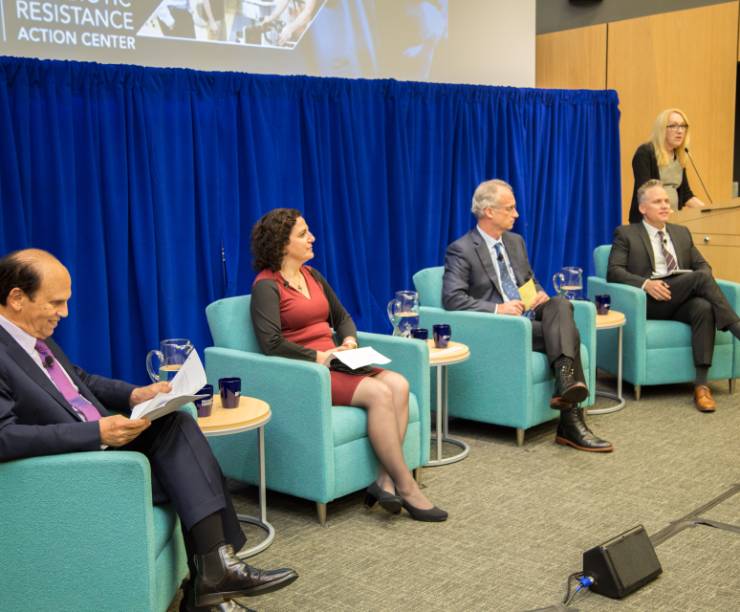 A panel of four policymakers and industry leaders sits in front of an audience, while Lynn Goldman, Dean of the Milken Institute SPH, speaks from a podium.