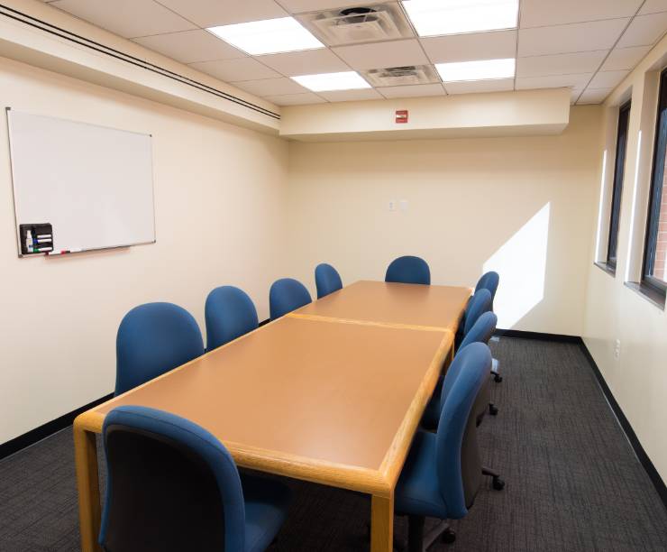 A group study room with windows, a large group table, and a whiteboard.