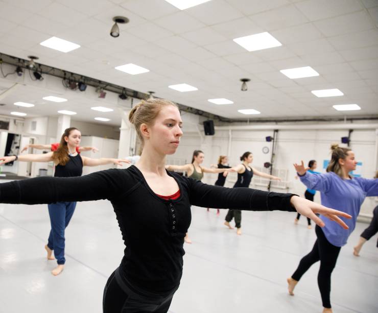 Several students dance in a classroom studio.