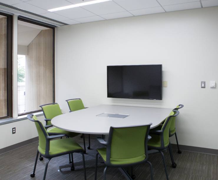 A table and chairs with large monitor mounted on the wall.